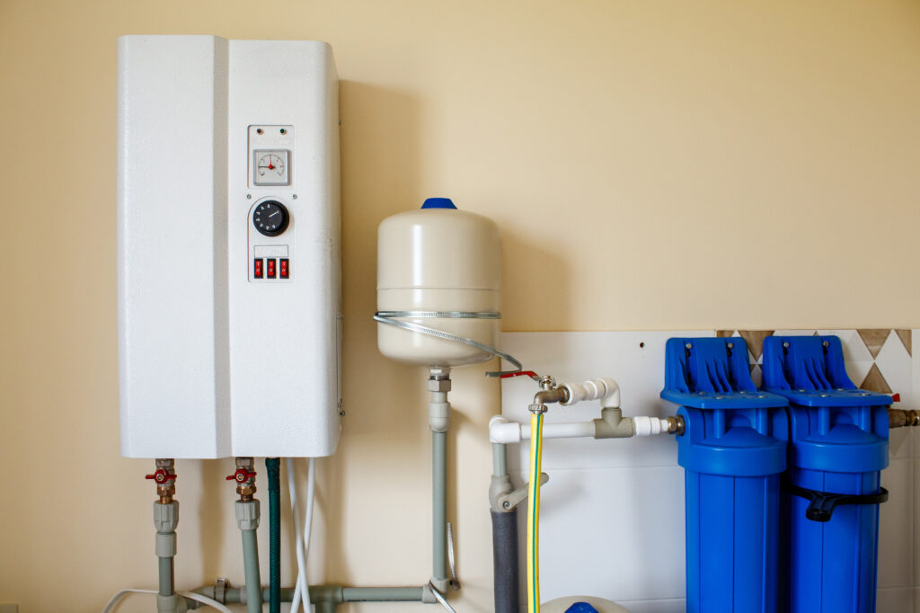 A tankless water heater system on an off-white wall.